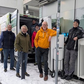 Team von effective world bei der Übergabe von Büromöbeln an die Ludwigswerkstätten, im Freien vor einem Fahrzeug